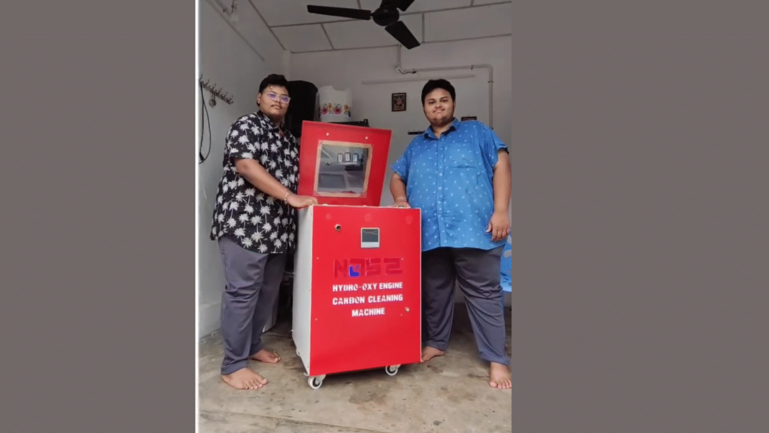 Two young men standing beside a red Hydro-Oxy Engine Carbon Cleaning Machine by Rupa Traders, designed for eco-friendly vehicle engine maintenance.